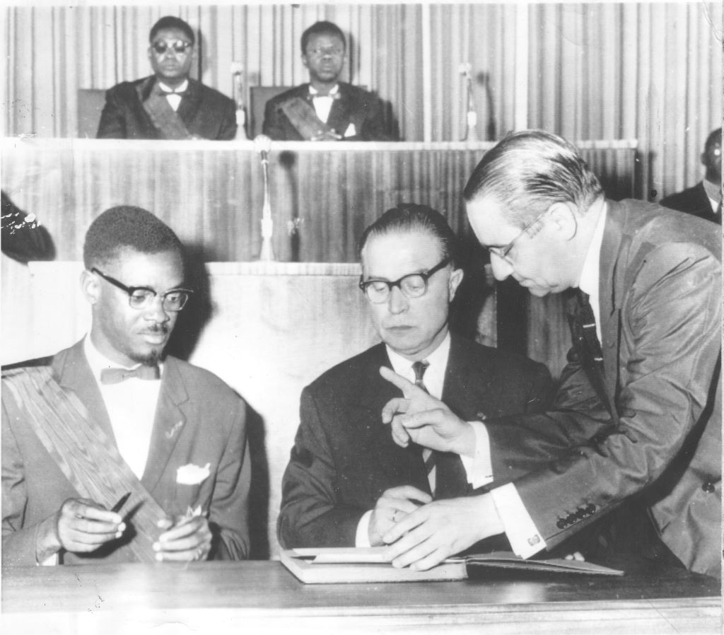 Patrice Lumumba s’apprêtant à signer l’Acte de l’indépendance sous l’œil du Premier ministre belge Gaston Eyskens, le 30 juin 1960.
